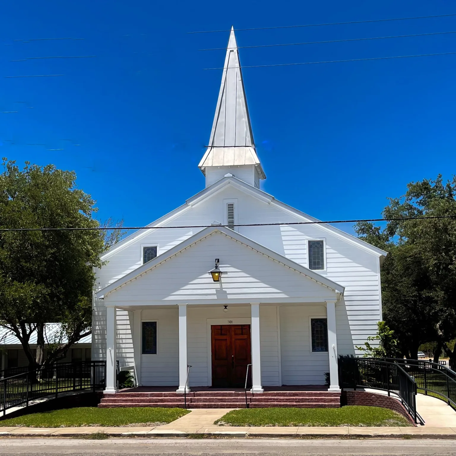 Small white church surrounded by trees with blue sky